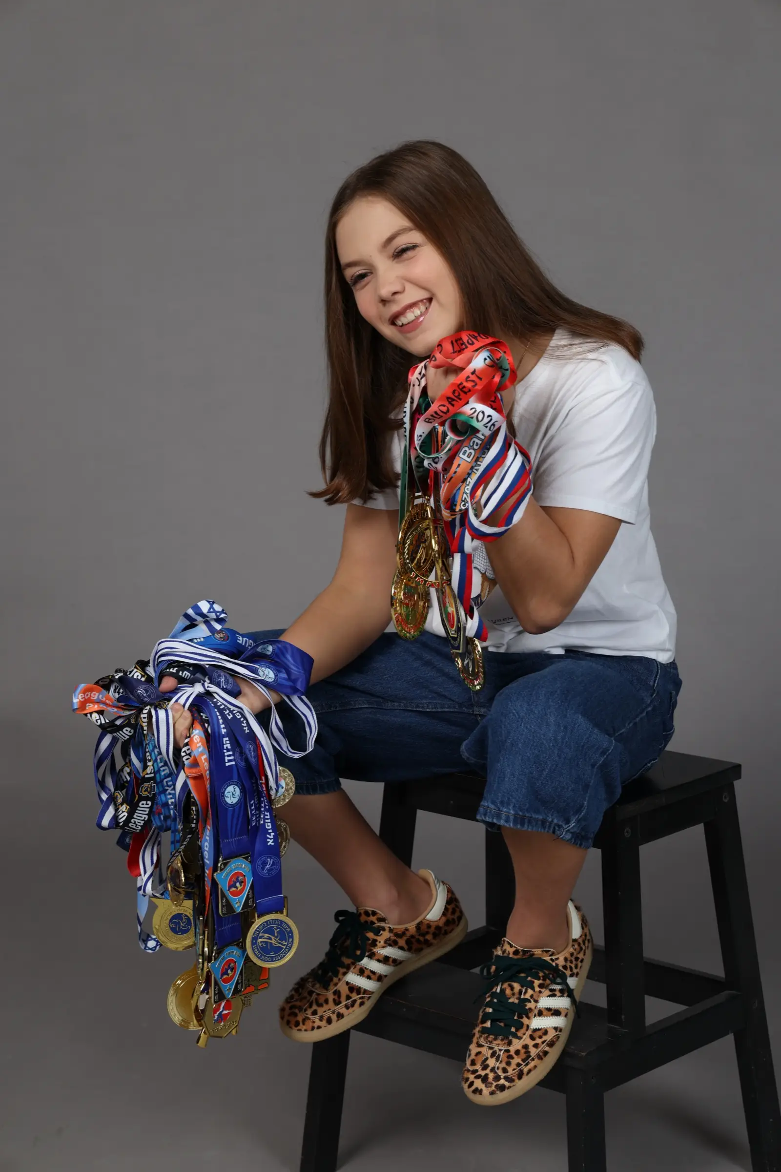 Melissa sitting and smiling with a pile of medals in her lap
