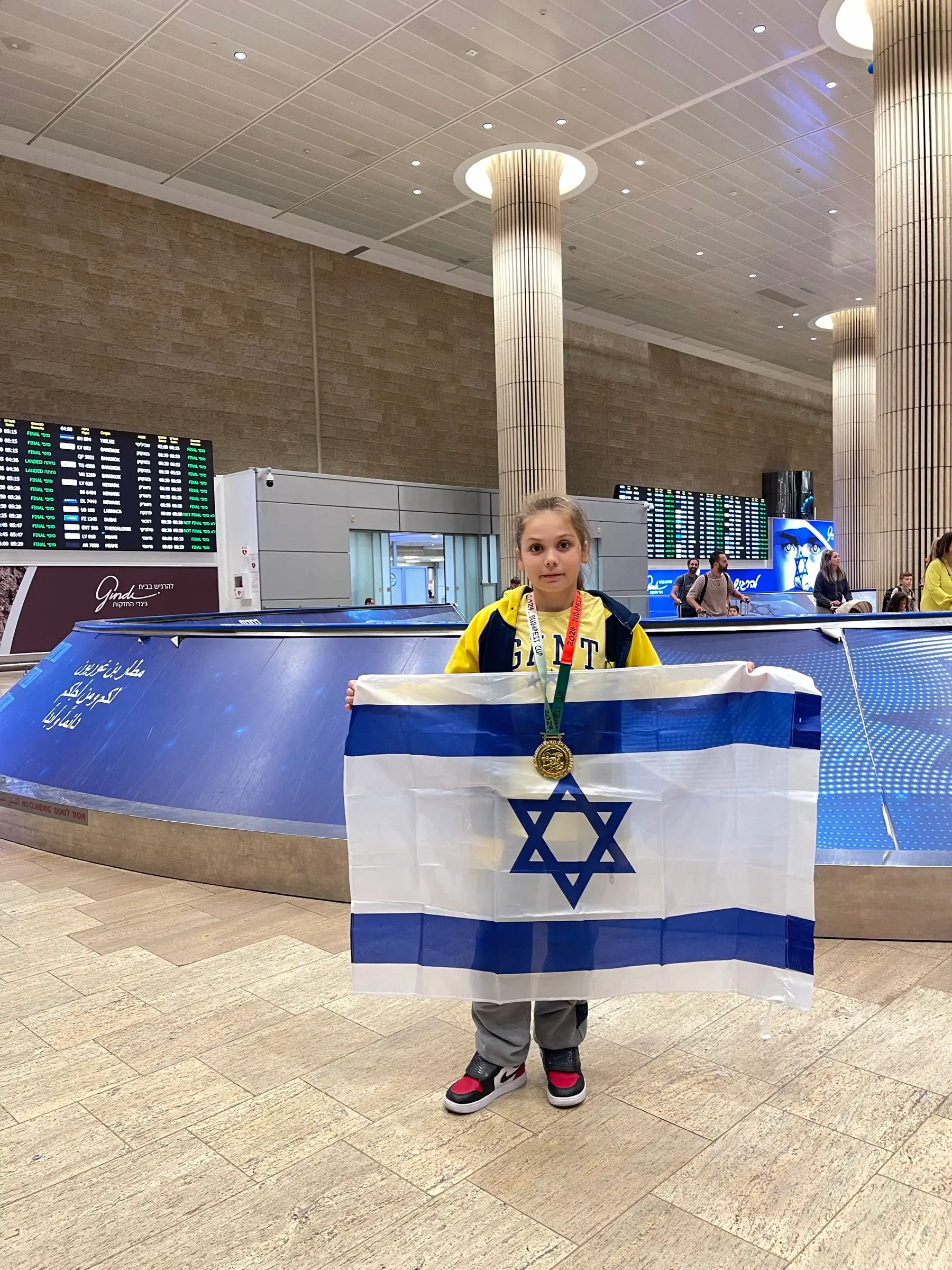 Melissa standing with an Israeli flag at an airport terminal