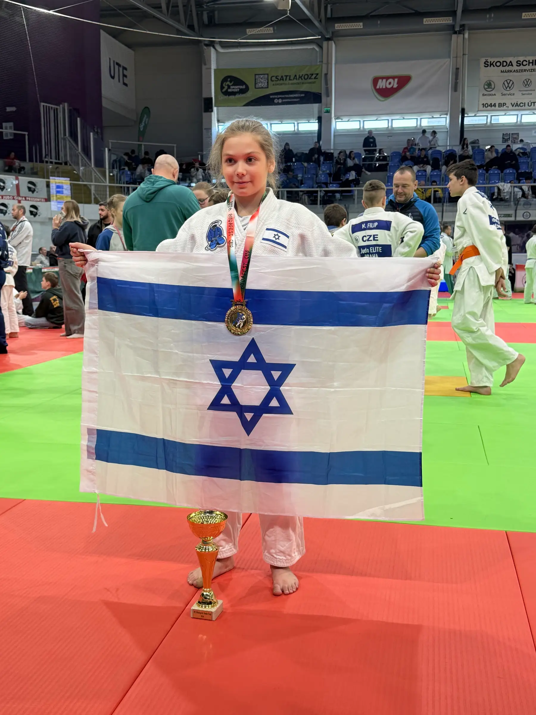 Melissa on the mat holding a big Israeli flag and a medal