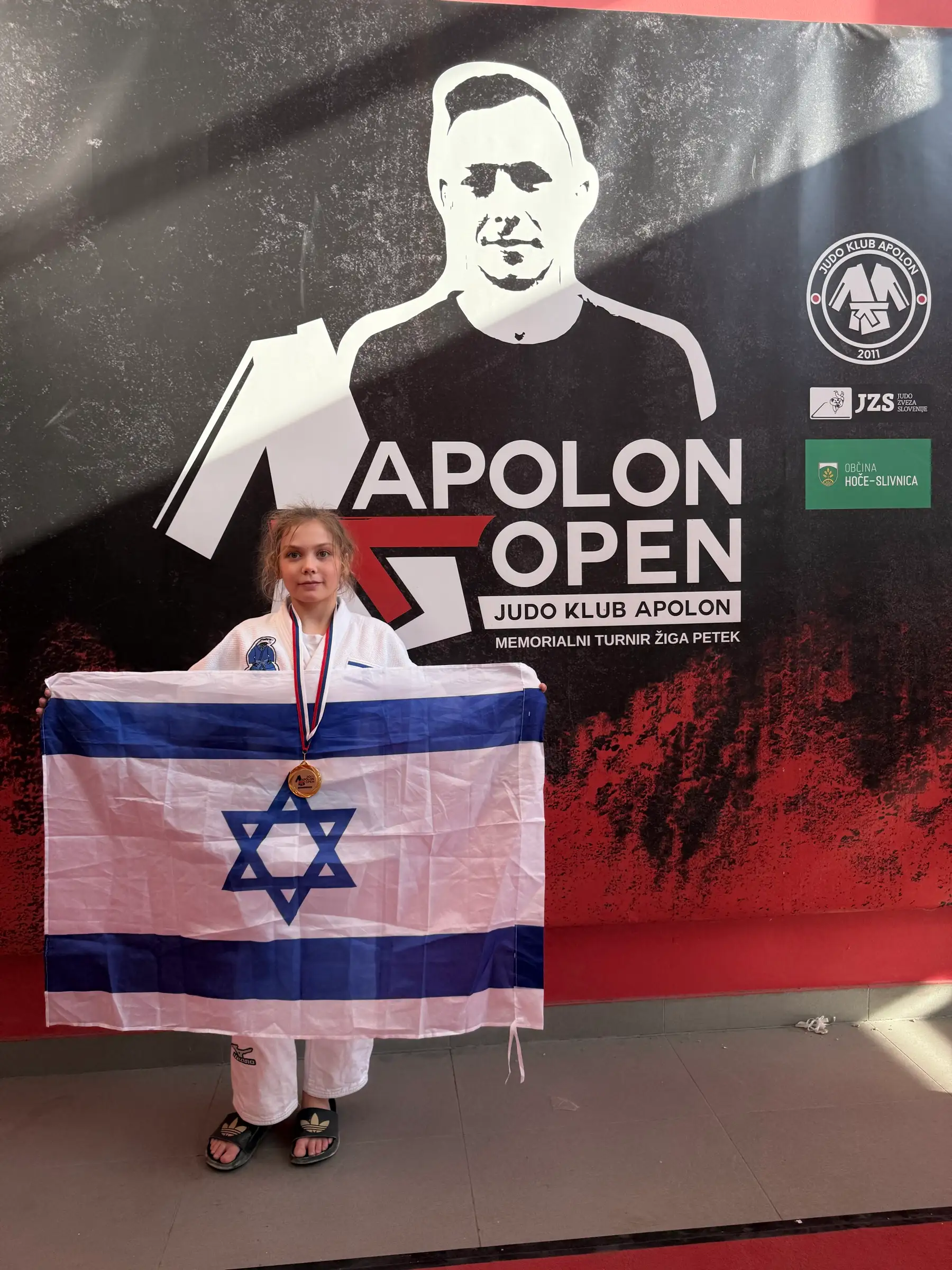 Melissa holding an Israeli flag in front of a competition sign