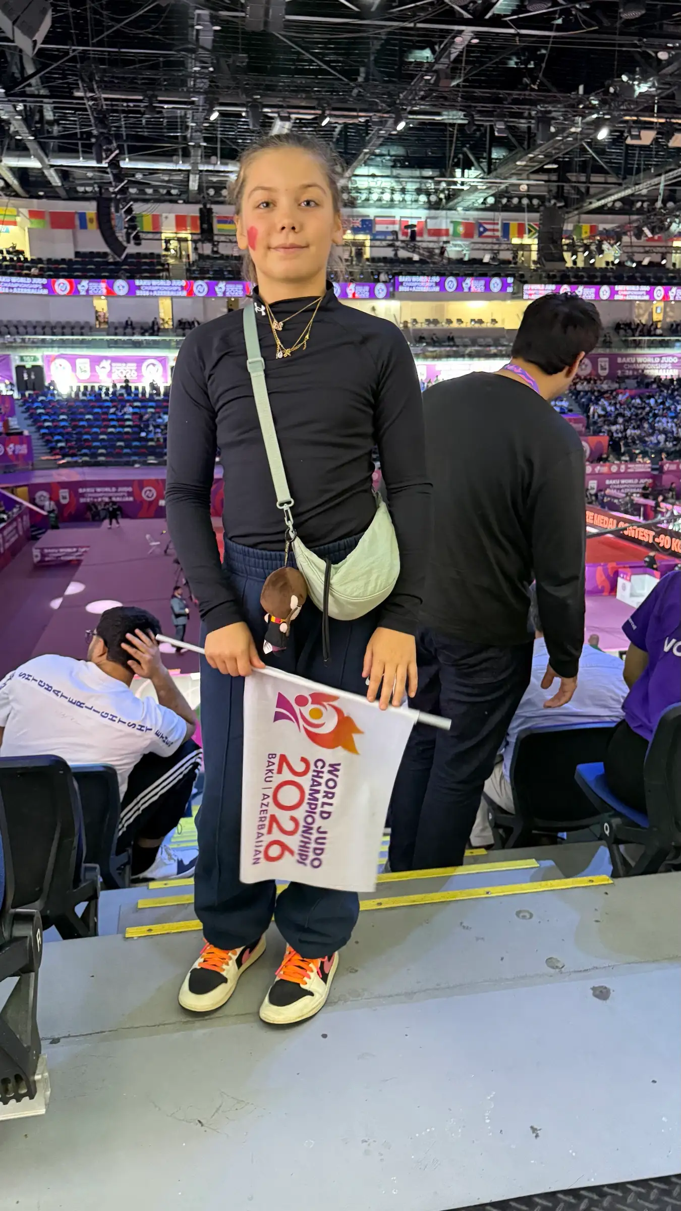 Melissa in the stands holding a paper flag of the 2026 championship