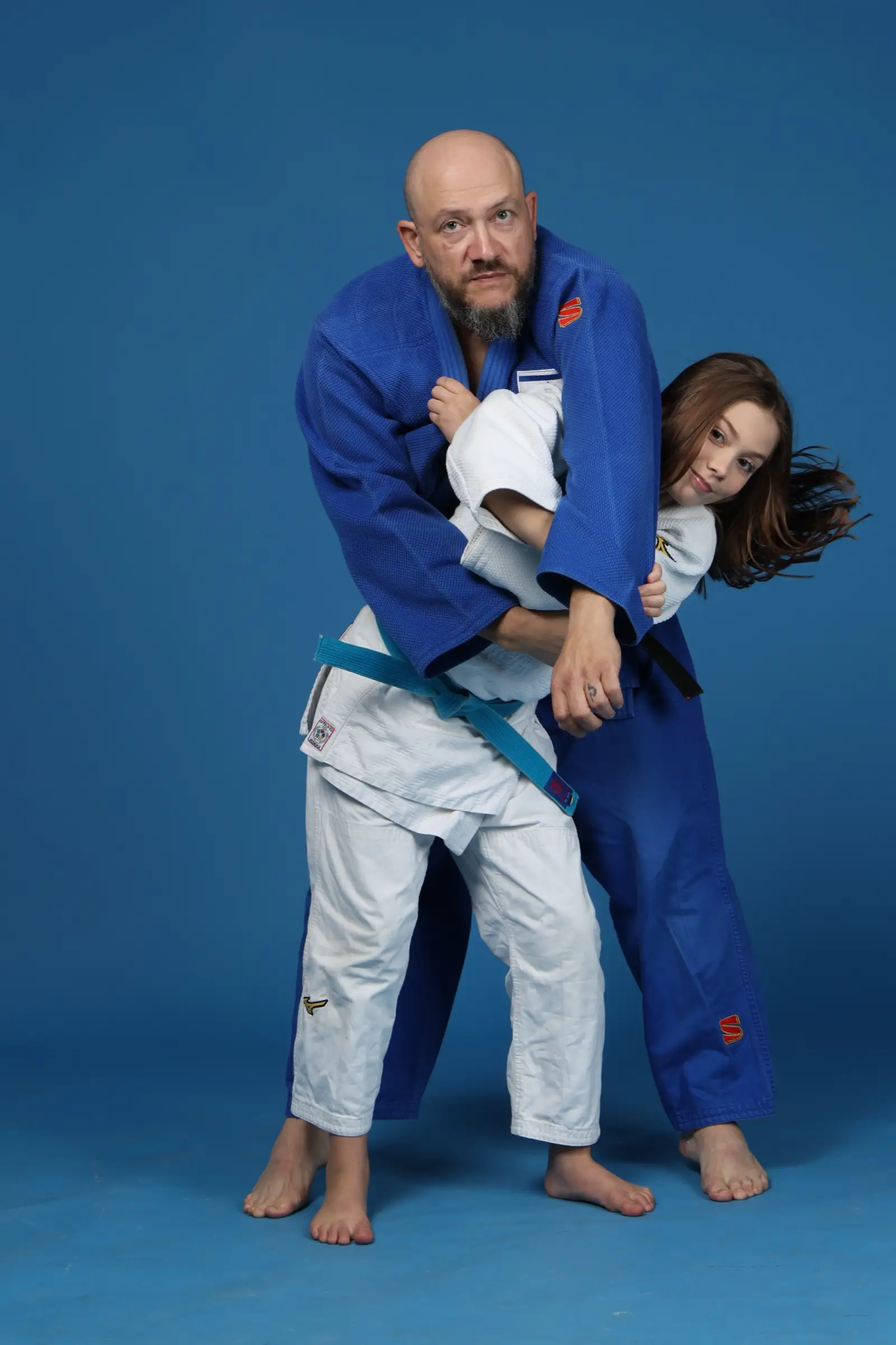 Melissa’s father throwing her in judo training, a studio shot on a blue background